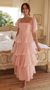 Detalle de vestido largo rosa con volantes, mangas abullonadas y escote cuadrado.