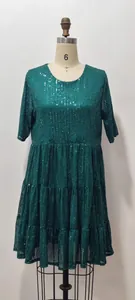 Vue détaillée d'une mini-robe à paillettes vertes avec ourlet à volants et col rond élégant