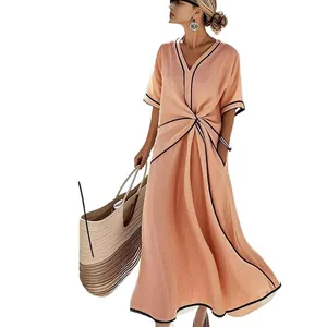 Detail view of elegant orange bohemian maxi dress with twisted waist and black trim.