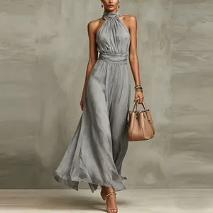 Elegant grey halter neck chiffon pleated maxi dress styled with a tan handbag for resort