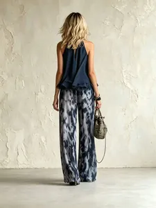 Vista posteriore donna in top blu e pantaloni a gamba larga in chiffon con stampa marmo