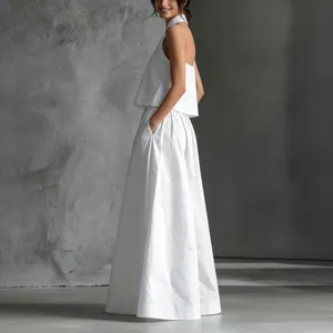 Vista lateral de elegante conjunto de top corto sin mangas y pantalones anchos blancos