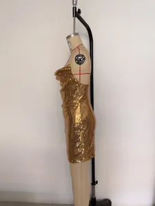 Close-up side view of a glamorous gold sequin backless mini dress displayed on a mannequin