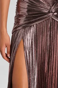 Detalle de un vestido plisado metálico oro rosa con abertura alta y nudo central