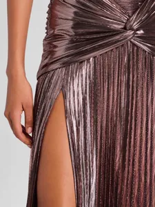 Detalle de elegante vestido plisado rosa metálico con un diseño de abertura lateral.