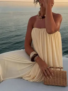 Detail of elegant cream strapless pleated maxi dress featuring a chic smocked design
