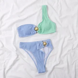 Detalle del conjunto de bikini bicolor con textura y adornos de conchas doradas.