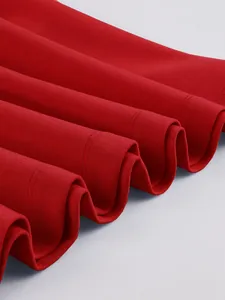 Macro detail of high-quality red textured fabric on a pleated swing dress hemline.