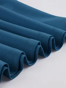Close-up of teal pleated dress hem showing fine fabric texture and neat stitching