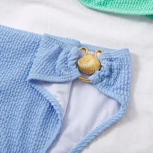 Detalle de la parte inferior de un bikini azul con textura ondulada y hebilla de concha.