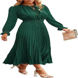 Detailed view of a green Swiss dot pleated midi dress featuring long sleeves and a tie-neck
