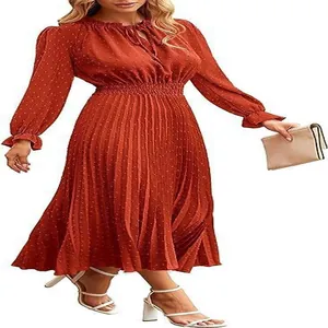 Detail of rusty orange Swiss dot pleated midi dress with long sleeves and elastic waist