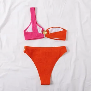 Detalle de bikini bicolor rosa y naranja de un solo hombro con textura ondulada