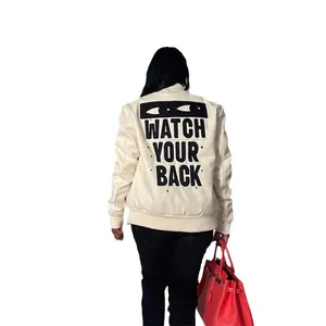 Women's apricot bomber jacket with black "WATCH YOUR BACK" graphic print on the back.