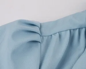 Detail showing the pleated waist and soft chiffon texture of a light blue dress