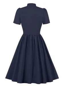Back view detail of a navy blue A-line dress highlighting the pleated skirt and waistline