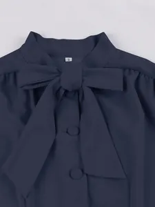 Close-up detail of the elegant navy blue dress collar featuring a bow-tie and buttons