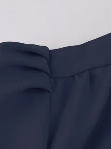 Close-up of the navy blue chiffon fabric and elegant tie-waist detail of the dress.