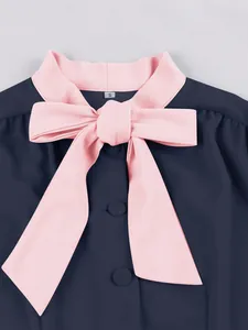 Close-up of navy blue dress featuring a pink contrast collar and elegant bow detail
