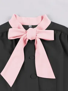 Detailed macro view of an elegant black dress featuring a large pink bow and contrast collar.