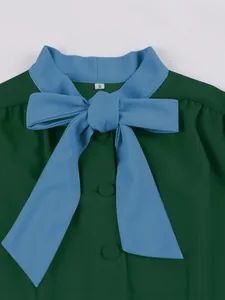 Detailed view of an elegant dark green dress with a large light blue bow-tie collar