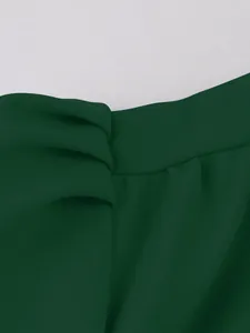 Close-up detail of dark green crepe fabric showing elegant tie design and fine texture