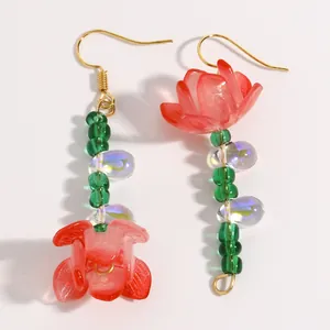 Detailed view of long drop earrings featuring red resin flower petals and green beads