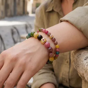 Detail view of colorful tourmaline beaded bracelets on wrist with gold accents
