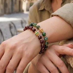 Close-up of bohemian style beaded elastic bracelets with green and red stones on a model's wrist