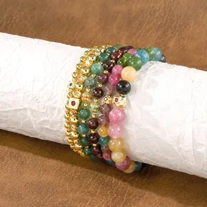 Close-up of handmade multi-color tourmaline and gold-toned beaded elastic bracelets