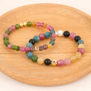 Detailed view of handmade multi-colored tourmaline beaded bracelets on a rustic wooden plate