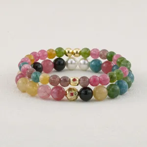 Close-up of multi-color tourmaline beaded bracelets with gold faceted charms.