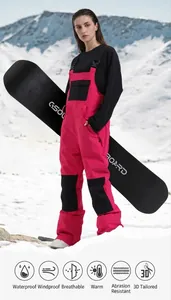 Professional women's pink waterproof ski bib overalls shown with snowboard in snow mountain