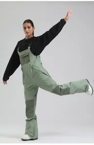 Action shot of women's olive green bib ski pants highlighting flexible fit