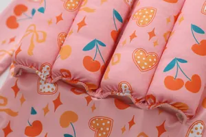 Detaillierte Makroansicht des rosa Kinder-Auftriebsbadeanzugs mit niedlichen Kirsch- und Herzmustern