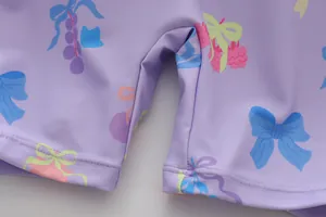 Detailansicht der feinen Nähte und Schleifenmuster auf einem lila Mädchen-Badeanzug.
