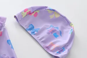 Detailansicht einer lila Kinderbadekappe mit farbenfrohen Frucht- und Schleifenmustern