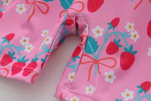 Detailansicht eines pinkfarbenen Mädchenbadeanzugs mit süßem Erdbeer- und Blumenmuster