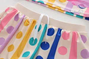 Detail view of colorful polka dot pattern and white drawstring on kids swimsuit bottoms.