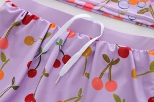 Close-up detail of purple children's swimwear with cherry print and white drawstring