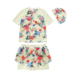 Detailed view of a three-piece floral girls swimsuit set with top, skirted shorts and cap