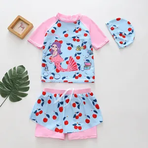Detailed view of girls' mermaid and cherry print two-piece swimsuit set with swim cap.