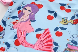 Detailed close-up view of the cute mermaid and cherry print on girls' swimsuit fabric