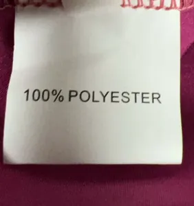 Detail van het witte onderhoudsetiket van 100% polyester op de paarse jurkvoering