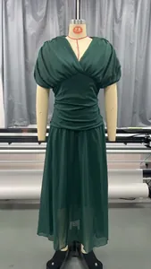 Detail van een elegante donkergroene maxi-jurk met V-hals, geplooide taille en pofmouwen