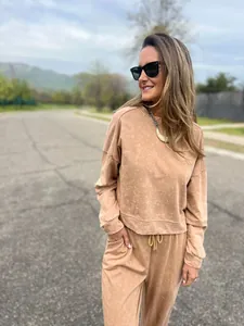 Model wears a casual beige acid-wash sweatshirt and jogger set on an outdoor road.