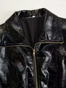 Macro detail of a black glossy crocodile embossed faux leather jacket with metal zipper.