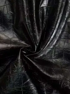 Macro detail of glossy black crocodile embossed faux leather fabric texture