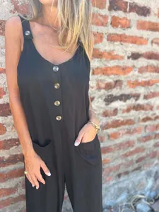 Detail of black sleeveless jumpsuit with wood-texture buttons and side pockets