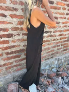 Side view of a casual loose black jumpsuit with pockets for women on a brick wall